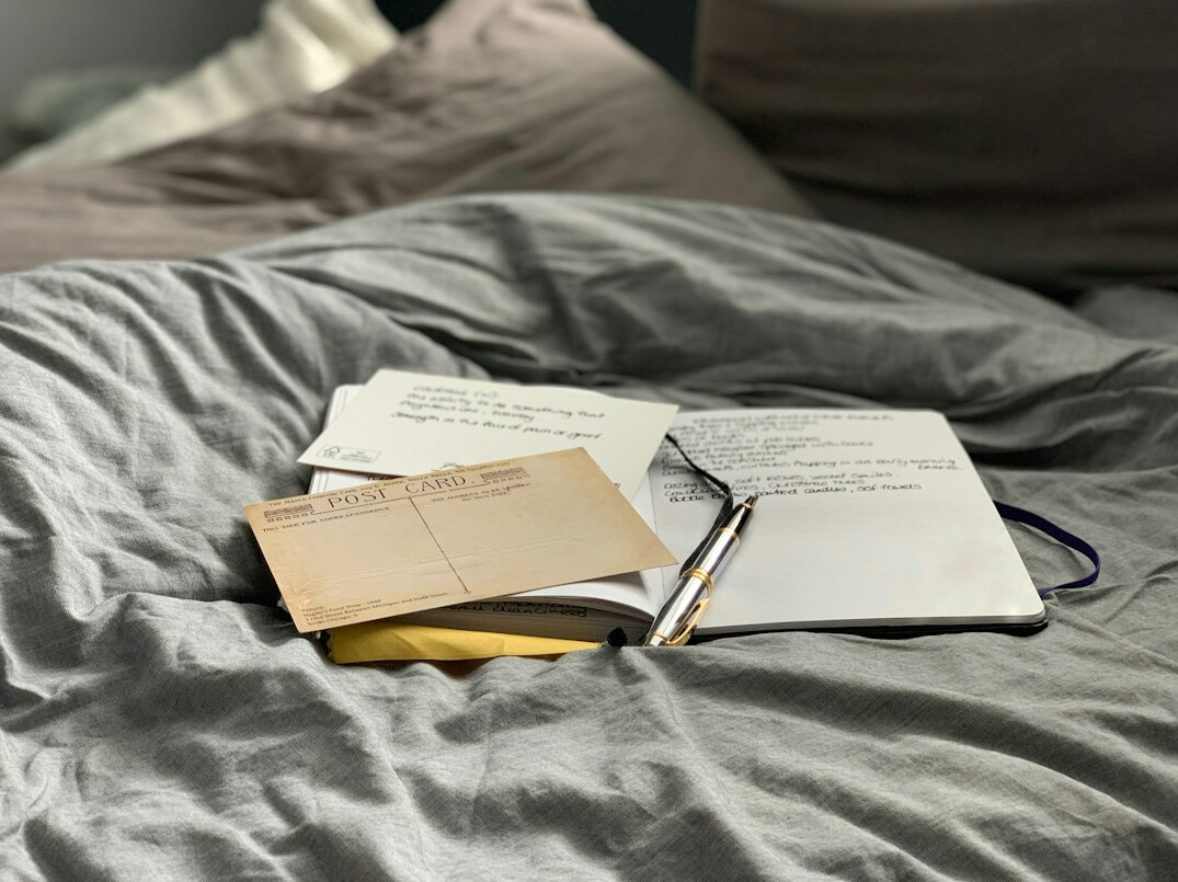 Journalist writing notes at a desk with a laptop